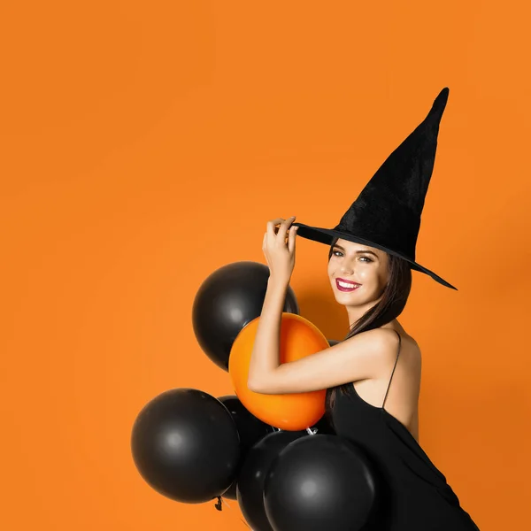 Gyönyörű nő visel boszorkány jelmez léggömbökkel Halloween party sárga alapon, hely a szöveges — Stock Fotó