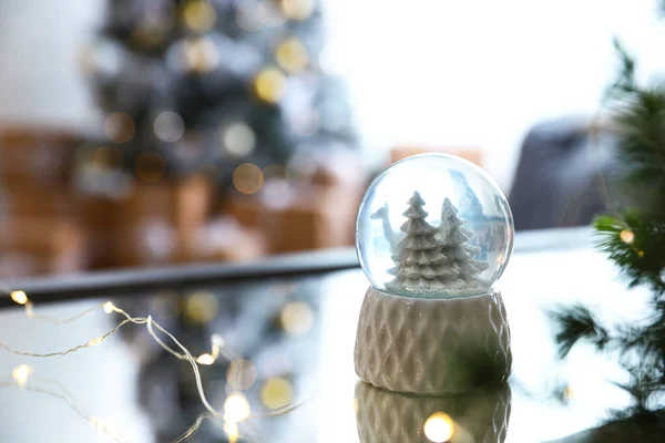 Декоративный рождественский снежный шар на зеркальной поверхности в помещении — стоковое фото