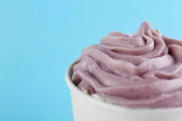 Tasse mit leckerem gefrorenem Joghurt auf hellblauem Hintergrund, Nahaufnahme. Raum für Text — Stockfoto
