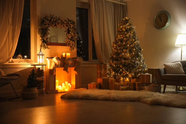 Stilvolles Interieur mit schönem Weihnachtsbaum und dekorativem Kamin in der Nacht — Stockfoto