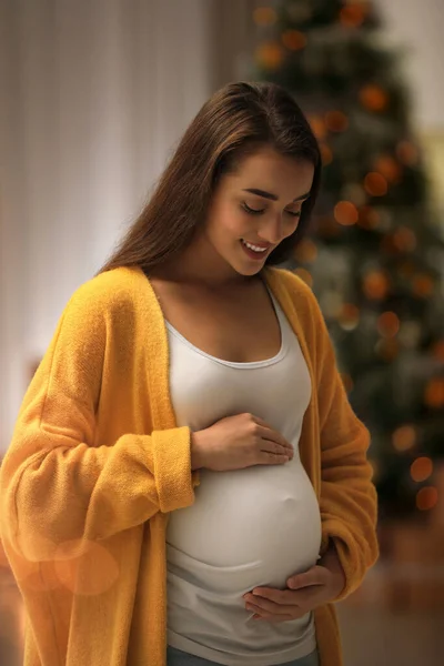 Mujer embarazada feliz y árbol de Navidad en el fondo. Esperando un bebé — Foto de Stock