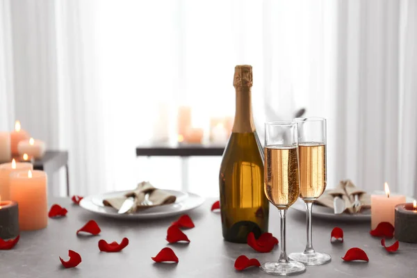 Romantische tafelschikking met brandende kaarsen en rozenblaadjes binnen — Stockfoto