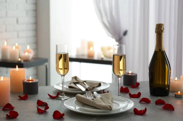 Romantische tafelschikking met brandende kaarsen en rozenblaadjes binnen — Stockfoto