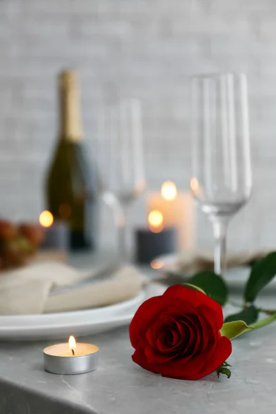 Палаюча свічка і червона троянда на сірому мармуровому столі в приміщенні — стокове фото