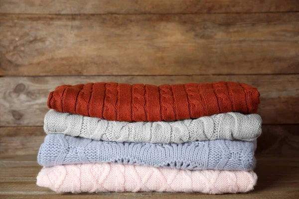 Tumpukan sweater di latar belakang kayu. Pakaian musim gugur — Stok Foto