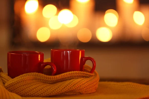 Чашки гарячого напою на в'язаному шарфі на розмитому фоні. Зимова атмосфера — стокове фото