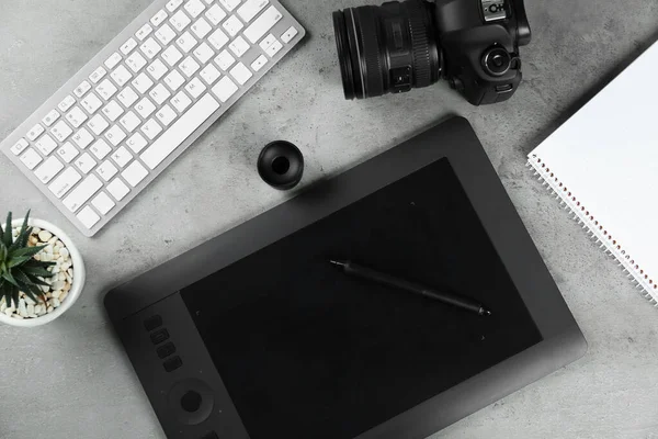 Plochá kompozice s grafickým tabletem a fotoaparátem na šedém kamenném stole, prostor pro text. Pracoviště návrháře — Stock fotografie