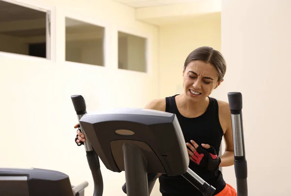 Young woman having heart attack on treadmill in gym