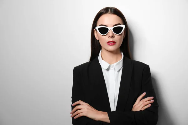 Młoda bizneswoman w stylowych okularach przeciwsłonecznych na jasnym tle, miejsce na tekst — Zdjęcie stockowe