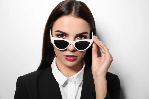 Joven mujer de negocios en gafas de sol con estilo sobre fondo claro — Foto de Stock