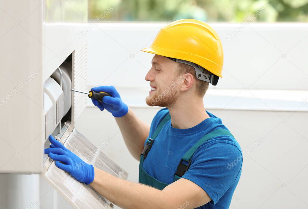 Professional technician maintaining modern air conditioner indoors