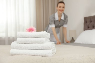 Yatakta bir yığın temiz havlu ve otel odasında oda hizmetçisi, yakın çekim. Metin için boşluk