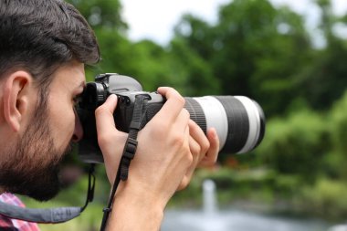 Fotoğrafçı parkta profesyonel kamerayla fotoğraf çekiyor.