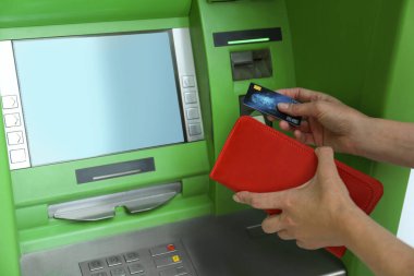 Modern ATM 'de cüzdanı ve kredi kartı olan olgun bir kadın, yakın plan.