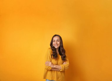 Sarı arka planda kalın kazaklı genç bir kadın, mesaj için yer var. Noel sezonu