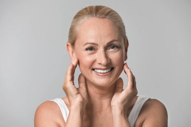 Gri arka plan üzerinde mükemmel bir cilde sahip güzel olgun kadın portresi