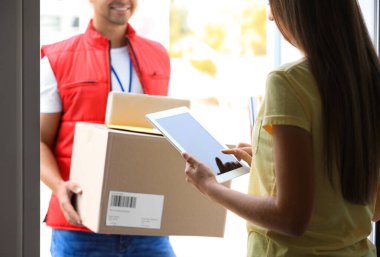 Kadın paket teslimatını doğrulamak için uygulamayı kullanıyor. Kapıda kurye var, yakın plan.