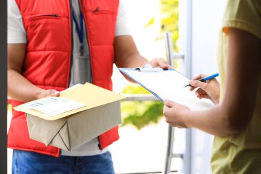 Kapıda paket teslim eden bir kadın var. Kapıya yakın. Kurye servisi