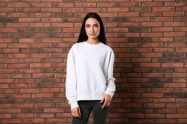 Portrait of young woman in sweater at brick wall. Mock up for design — Stock Photo, Image
