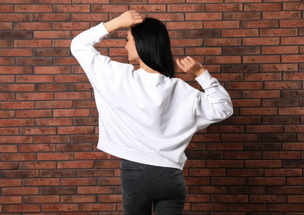 Fiatal nő pulóvert a téglafal. Kigúnyolják a tervezés — Stock Fotó