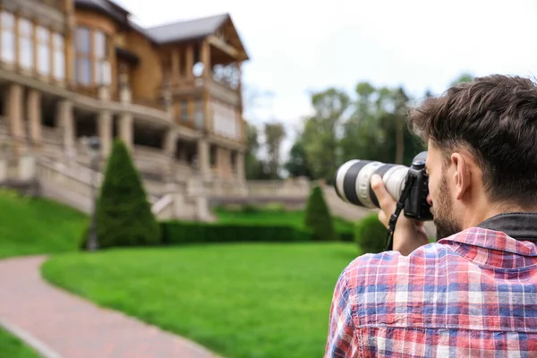 Fotógrafo tomando fotos de una hermosa casa con cámara profesional al aire libre —  Fotos de Stock