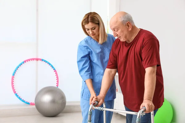 Caretaker helpen oudere man met Walking frame binnenshuis — Stockfoto