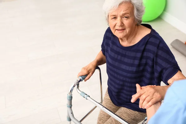 Caretaker helpen oudere vrouw met Walking frame binnenshuis — Stockfoto