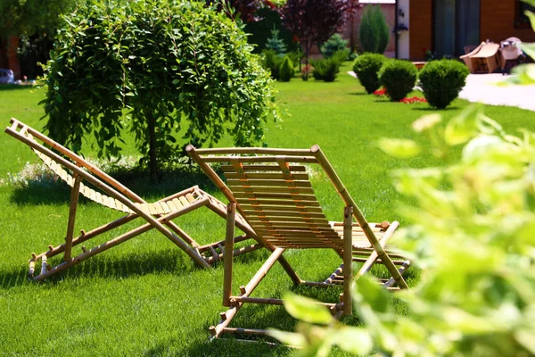 Drewniane leżaki w pięknym ogrodzie w słoneczny dzień — Zdjęcie stockowe