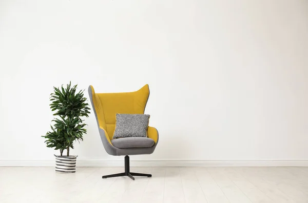 Стильний інтер'єр вітальні зі зручним кріслом і кімнатним рослиною біля білої стіни. Простір для тексту — стокове фото