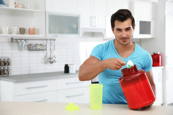 Jeune homme athlétique préparant une boisson protéinée dans la cuisine, espace pour le texte — Photo