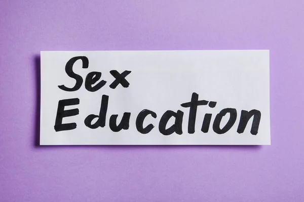 Pièce de papier avec phrase "SEX EDUCATION" sur fond violet, vue du dessus — Photo