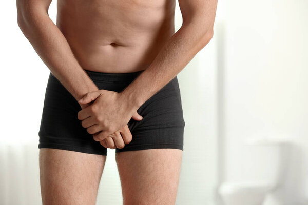 Man suffering from pain indoors, space for text. Urology problems