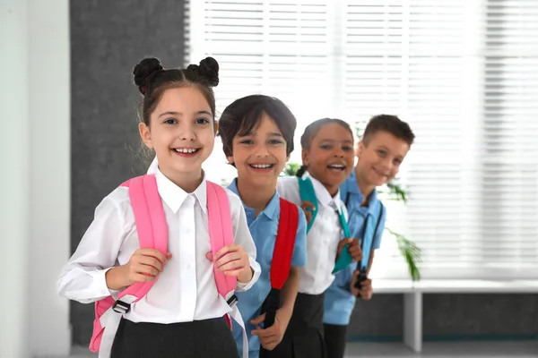 실내 배낭이있는 학교 유니폼을 입은 행복한 아이들 — 스톡 사진