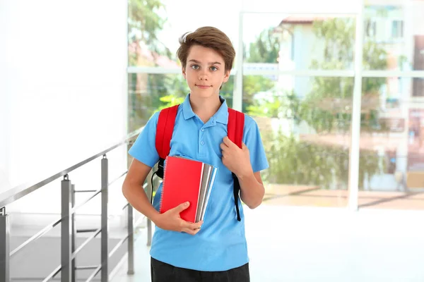 Glad pojke i skoluniform med ryggsäck inomhus — Stockfoto