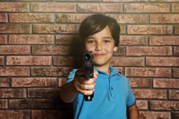 Małe dziecko bawiące się bronią przy murze. Gry Niebezpieczne gry — Zdjęcie stockowe