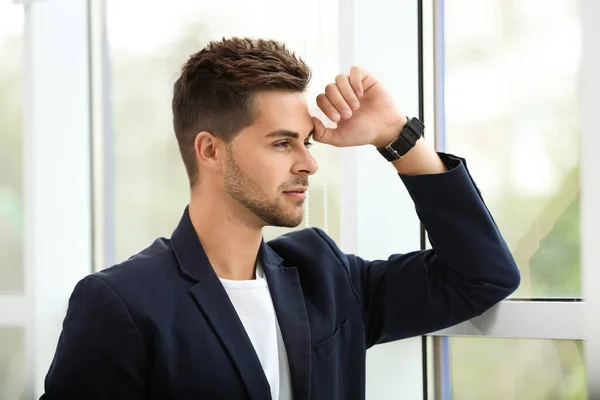 Retrato de joven guapo mirando por la ventana en el interior — Foto de Stock