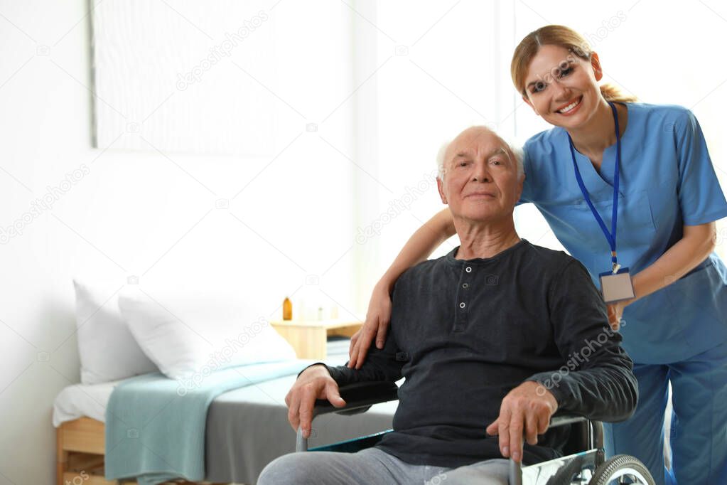 Nurse assisting elderly man in wheelchair indoors. Space for text