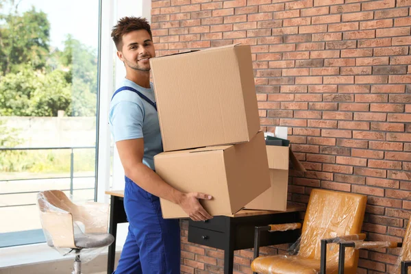 Молодой рабочий с картонными коробками в офисе. Услуги по перевозке — стоковое фото
