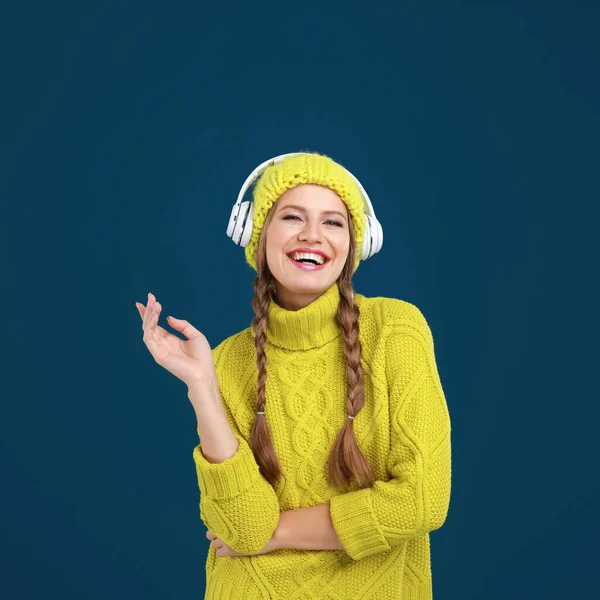 Jovem mulher ouvindo música com fones de ouvido no fundo azul escuro — Fotografia de Stock