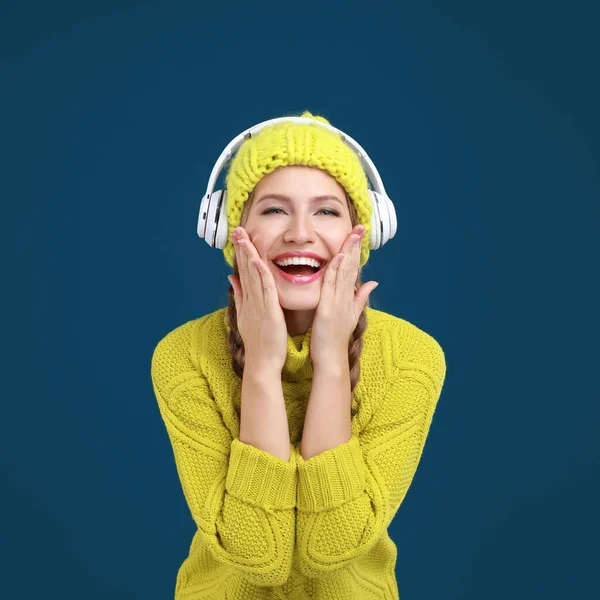 Mladá žena poslouchá hudbu se sluchátky na tmavomodrém pozadí — Stock fotografie