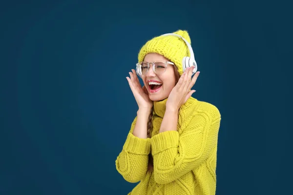 Jovem mulher ouvindo música com fones de ouvido no fundo azul escuro — Fotografia de Stock