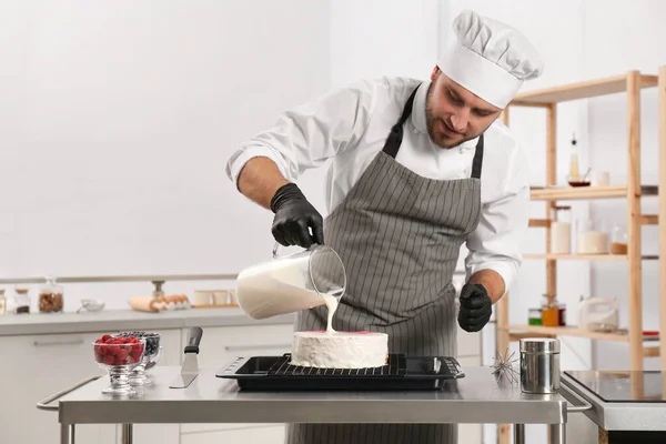 Male pastry chef preparing cake at table in kitchen