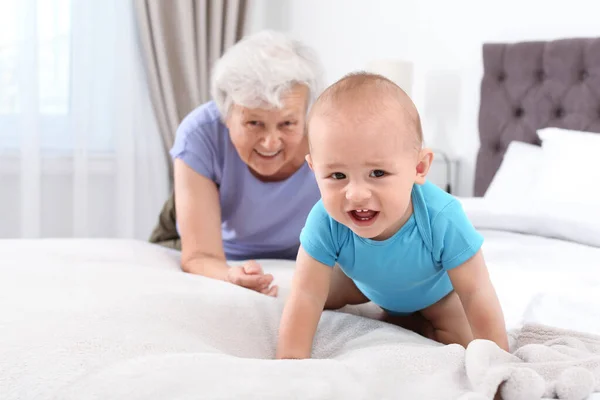 Lindo bebé con abuela feliz en el dormitorio —  Fotos de Stock