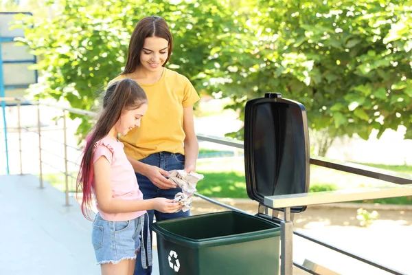 Η μητέρα και η κόρη της πετάνε χαρτί στον κάδο ανακύκλωσης έξω. — Φωτογραφία Αρχείου