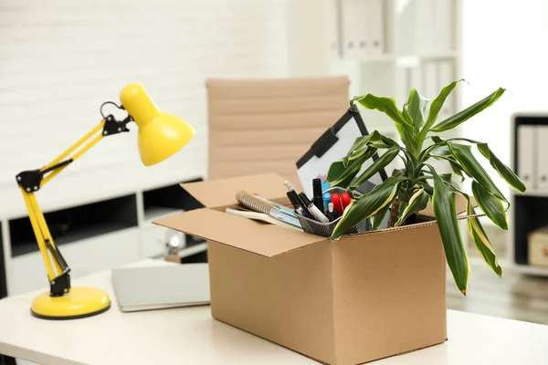 Boîte en carton pleine de choses sur la table dans le bureau — Photo