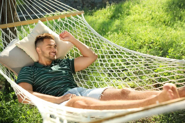 Young man resting in comfortable hammock at green garden — Stock Photo, Image