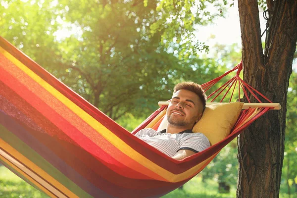 Jonge man rusten in comfortabele hangmat in groene tuin — Stockfoto