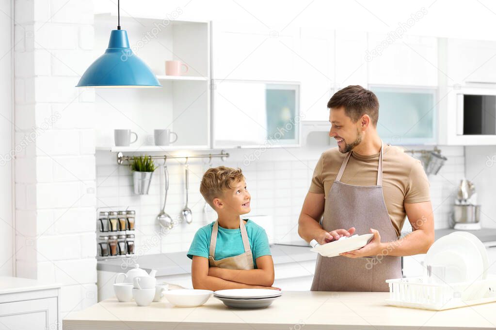 Dad and son wiping dishes in kitchen