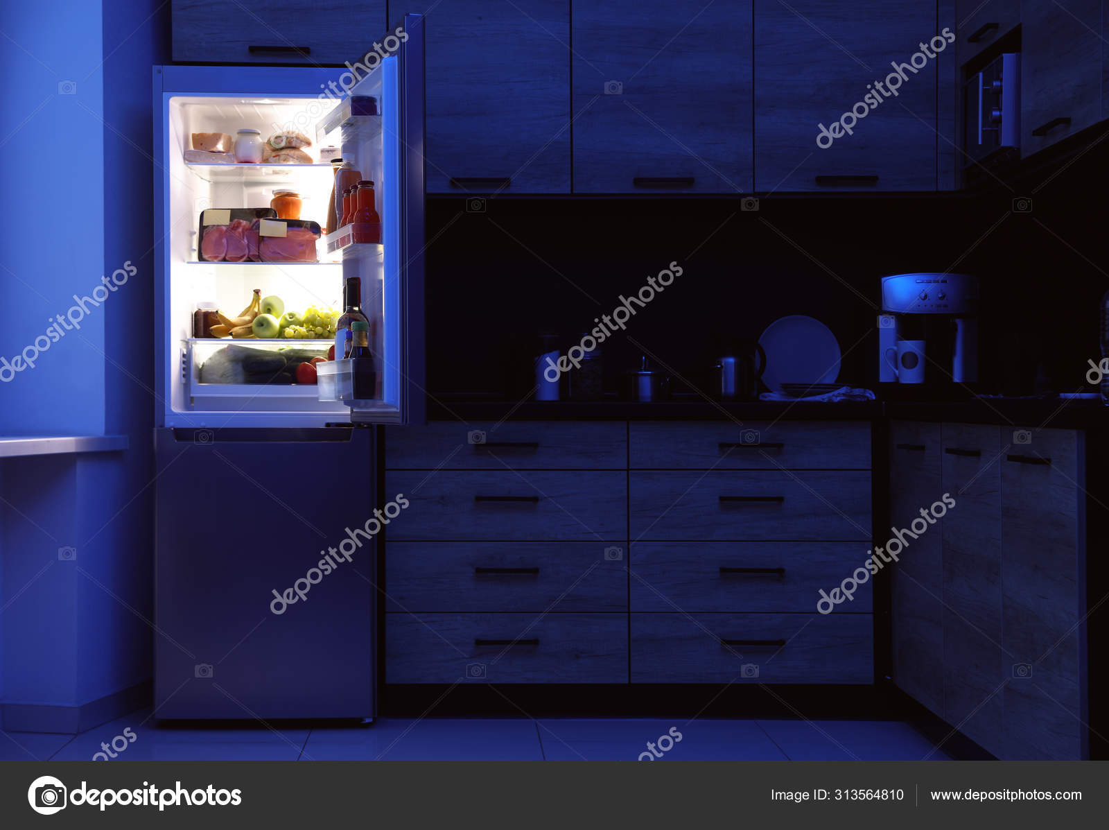 Open refrigerator full of products in kitchen at night Stock Photo by