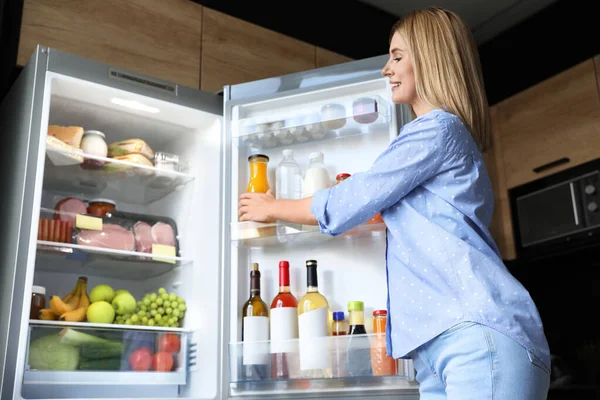 Mujer tomando botella con jugo de la nevera en la cocina — Foto de Stock